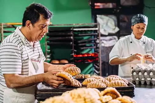 Baker sorting out Mexican sweet bread, known as Conchas, on trays for display